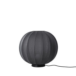 Rund sort lampe med strikket tekstur og moderne æstetik, placeret i gulvhøjde.